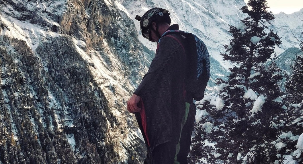 A wingsuit BASE jumper standing on the edge of a cliff in Lauterbrunnen, Switzerland